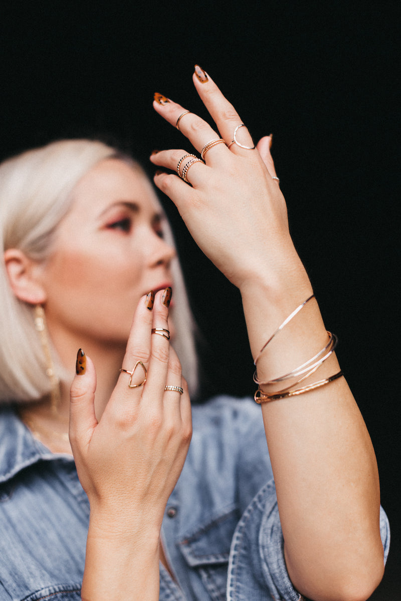 Model wears the bangle bracelet set with stacks of rings