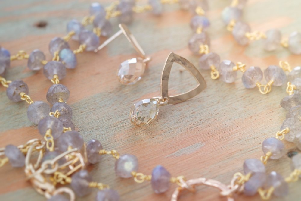 Kenda Kist Open Triangle Studs lay amongst semi-precious stones