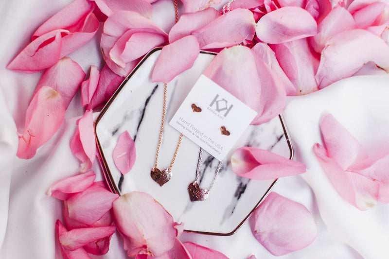 Among rose petals lay the heart stud earrings, heart pendant necklace and heart bracelet set