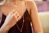 Model wears the Kenda Kist Triangle Ring with layers of Talia disc necklaces