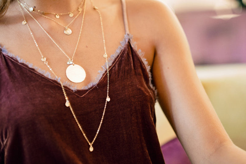 Model layers the Medallion Necklace with the Talia Five Disc Necklace and Talia 10 Disc Necklace