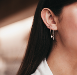 Model wears the lightning bolt and cross charm huggies hoops with moon studs