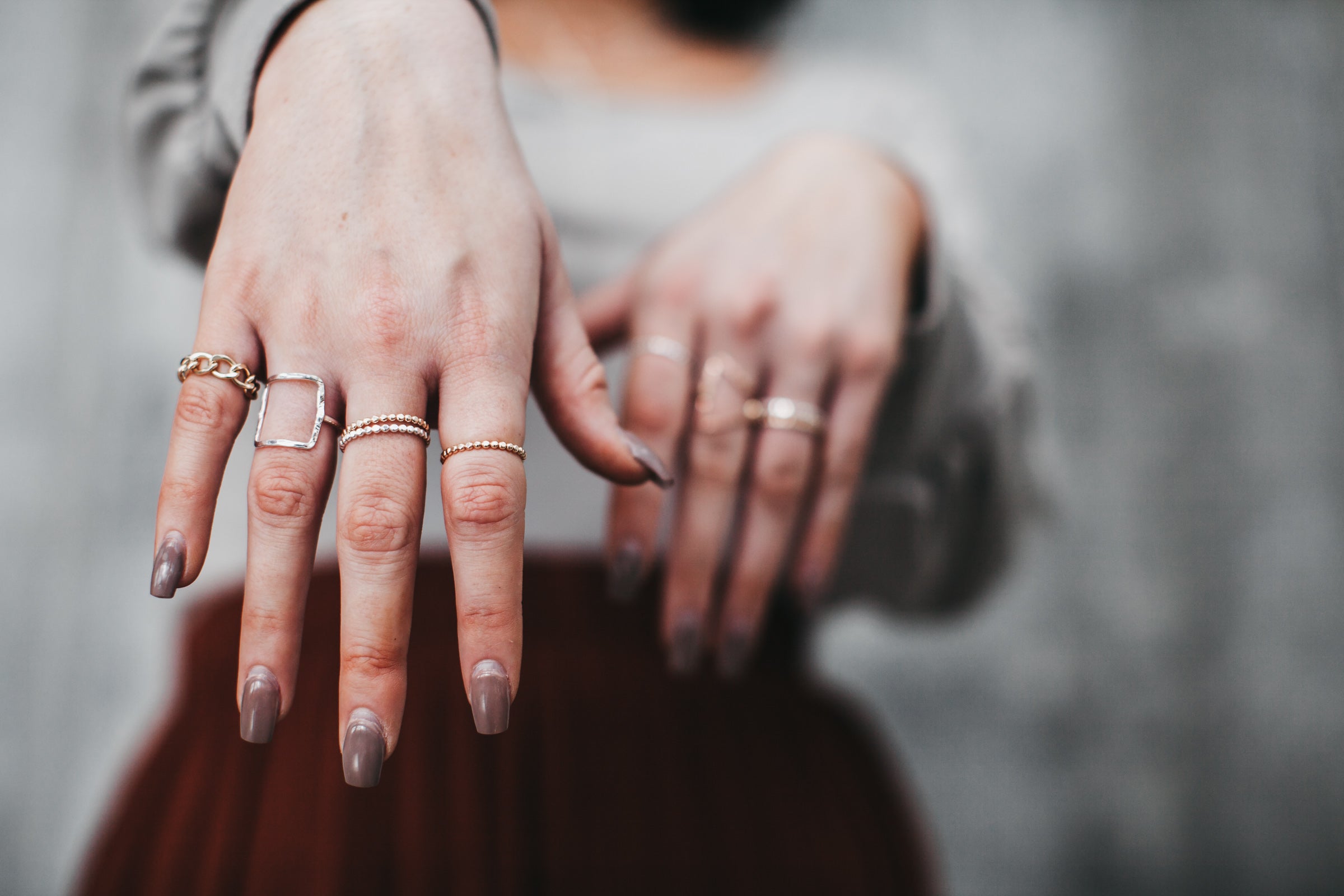 Model wears the large square ring with beaded band rings and chain ring